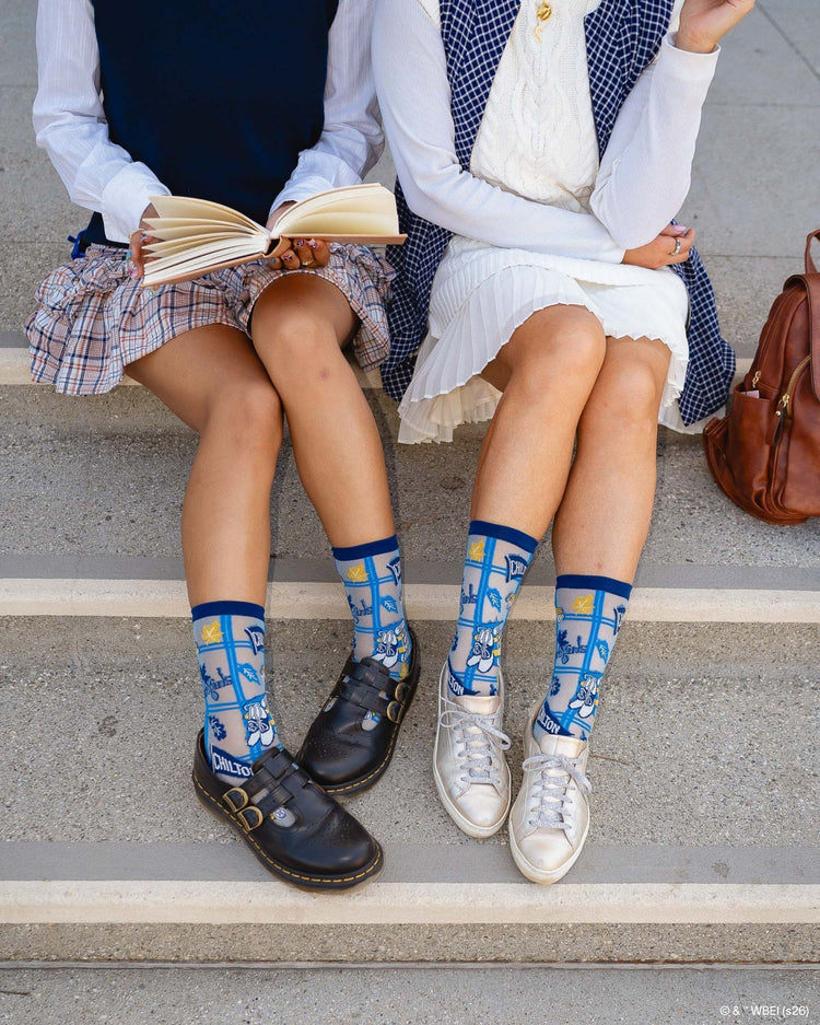 Two women wearing Sock Candy Gilmore Girls Chilton plaid sheer crew socks in a preppy aesthetic, styled with black leather Doc Martens and silver sneakers.