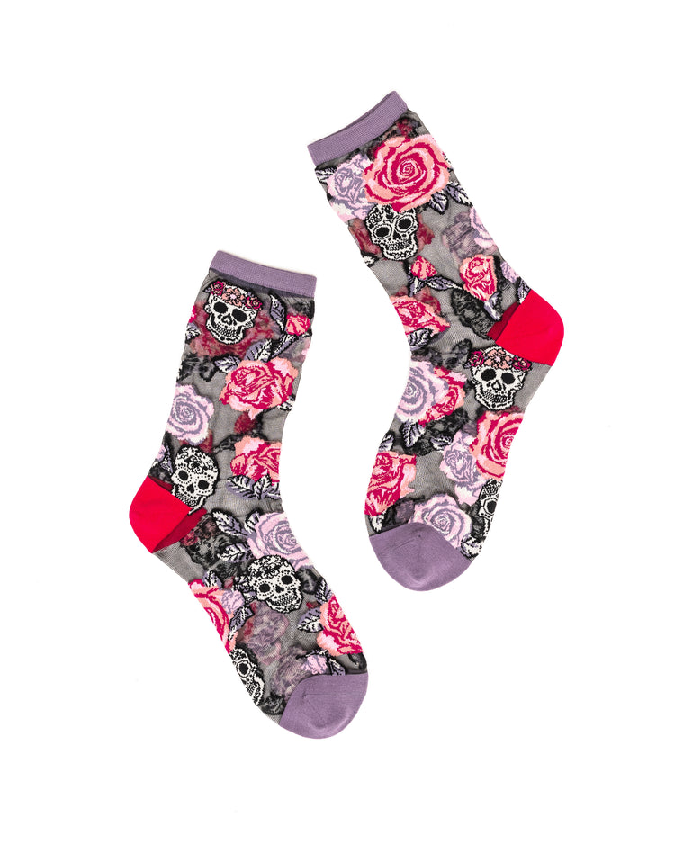 A pair of sheer Sock Candy socks with floral and skull pattern on a white background.