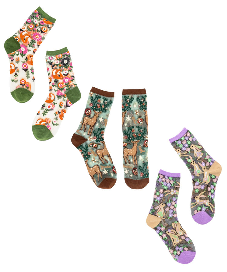 The Woodland Creatures sheer sock bundle by Sock Candy featuring three pairs detailed with orange foxes, brown deer, and jumping bunnies amidst colorful floral prints.