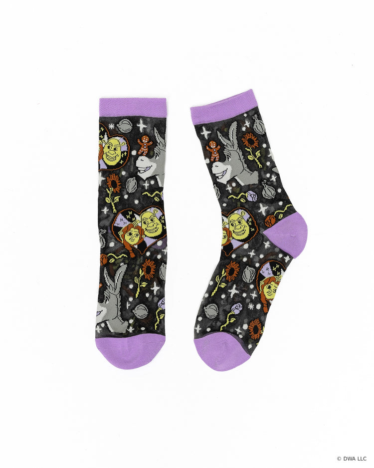 A pair of black sheer Shrek fashion socks designed by Sock Candy featuring Donkey, Gingy, and Shrek and Fiona surrounded by a design motif of onions, florals, and stars on a white background.